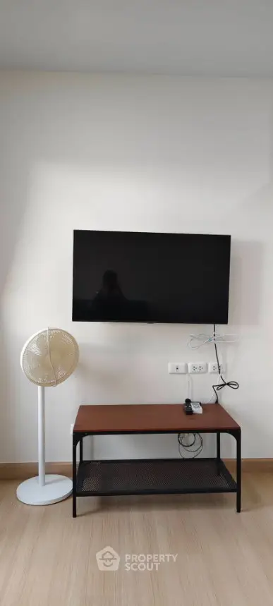 Modern living room with wall-mounted TV and sleek furniture setup.