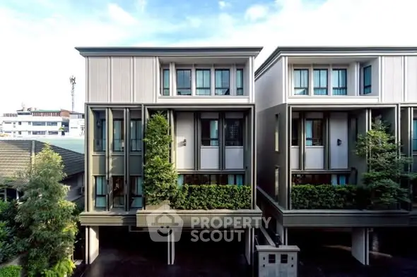 Modern townhouse exterior with sleek design and greenery accents in urban setting.
