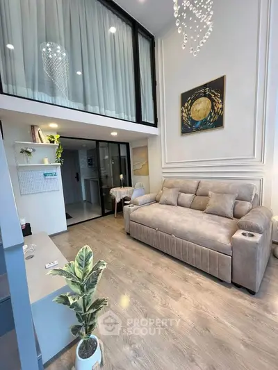 Modern living room with high ceiling and mezzanine, featuring elegant decor and cozy seating.