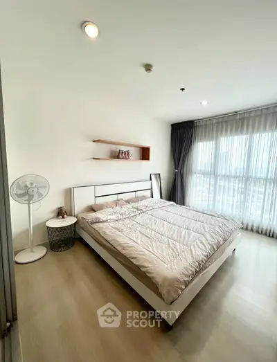 Spacious bedroom with large window and modern decor in a high-rise apartment.