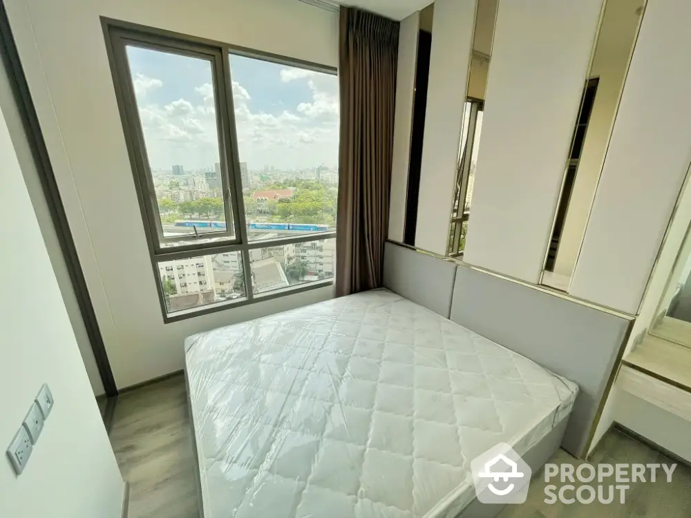 Modern bedroom with large window offering stunning city view and ample natural light.