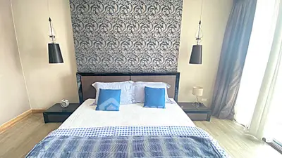 Modern bedroom with stylish decor and natural light, featuring a comfortable bed and elegant lighting.