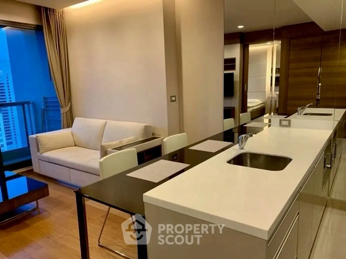 Modern open-layout kitchen and living room with balcony view in luxury apartment.