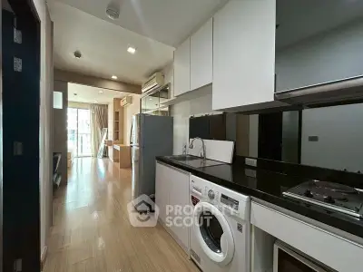 Modern kitchen with sleek appliances and open layout leading to a bright living area with balcony view.