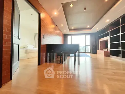 Spacious modern living room with wooden flooring and large windows offering natural light.