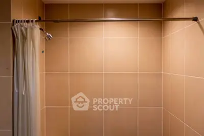 Modern bathroom shower area with tiled walls and curtain rod.