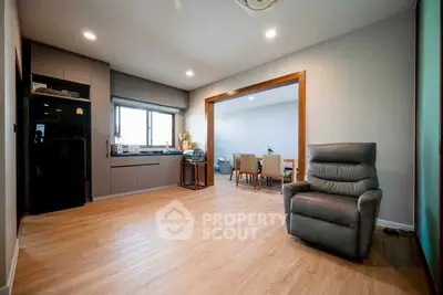 Spacious open-plan living room with modern kitchen and dining area, featuring sleek appliances and elegant flooring.