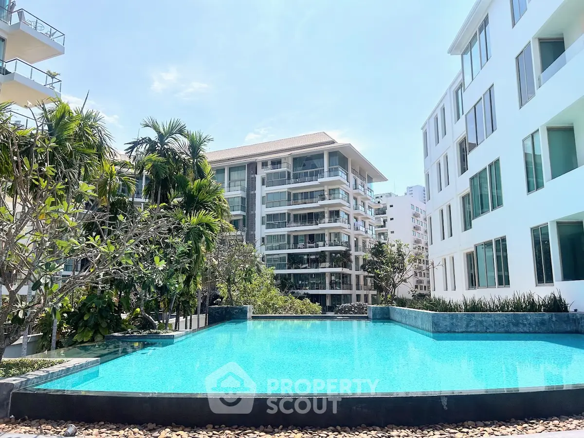 Luxurious apartment complex with stunning pool and lush greenery, offering a serene urban oasis.
