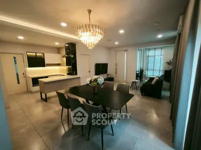 Luxurious open-plan living and dining area with elegant chandelier and modern kitchen.