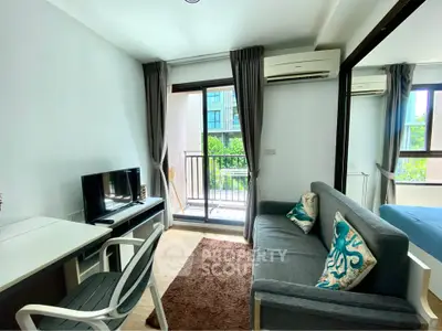 Modern living room with balcony view, stylish decor, and natural light in urban apartment.