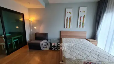 Modern bedroom with wooden flooring, stylish decor, and ample natural light from large windows.