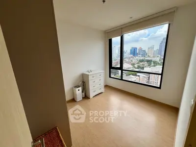 Spacious bedroom with city view, featuring large window and wooden flooring.