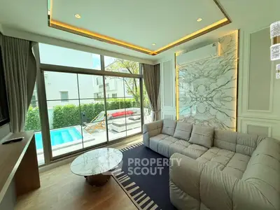 Luxurious living room with pool view, modern decor, and cozy seating area.
