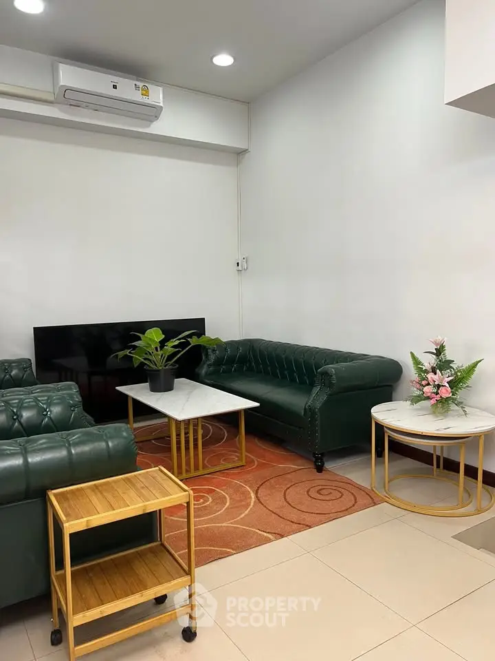 Stylish living room with green leather sofas, modern decor, and elegant coffee tables.