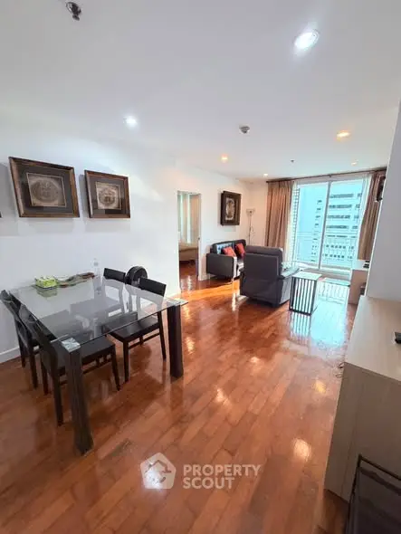 Spacious open-plan living and dining area with wooden flooring and modern decor in a high-rise apartment.