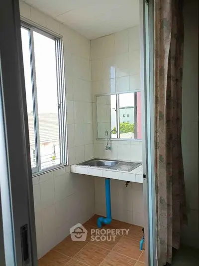 Bright utility room with large window and sink, perfect for laundry or storage.