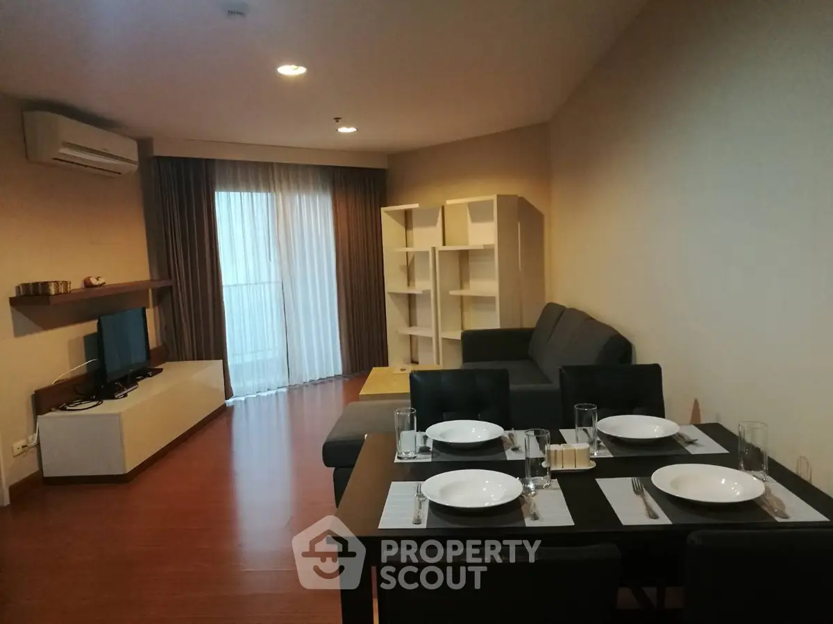 Spacious living room with dining area, modern furniture, and natural light from large window.