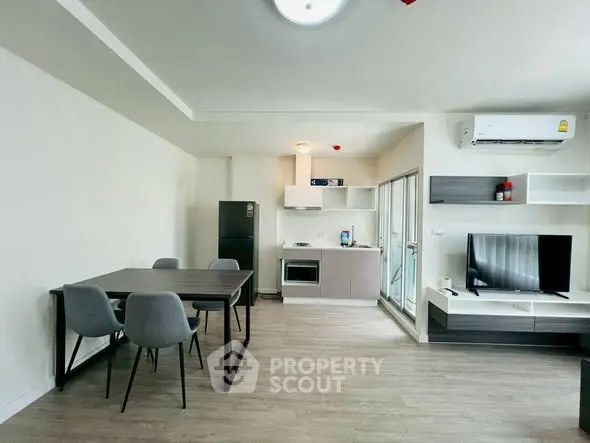 Modern open-plan living room with dining area and kitchen, featuring sleek furniture and appliances.