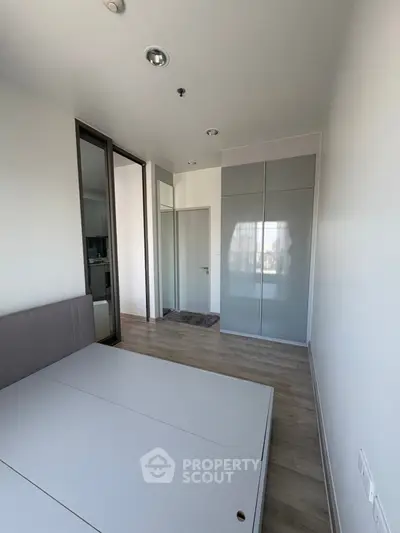 Modern bedroom with sleek design and ample natural light, featuring built-in wardrobe and minimalist decor.