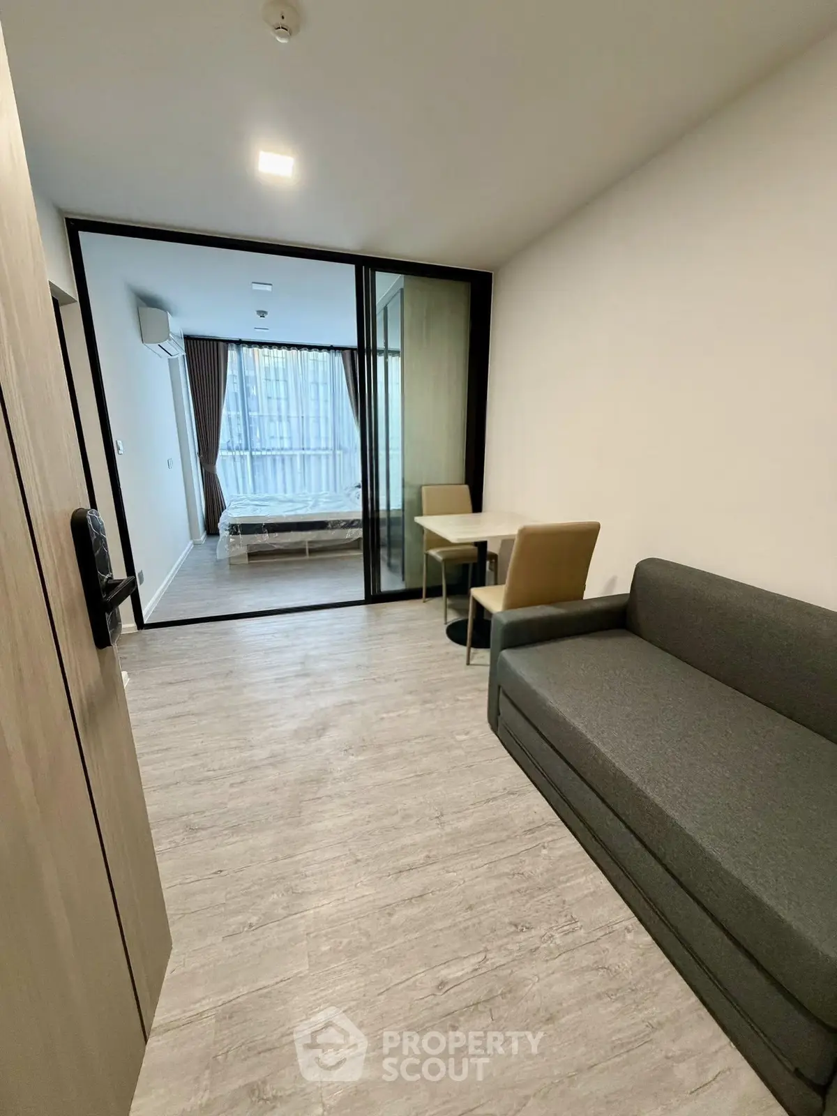 Modern studio apartment with glass partition, cozy sofa, and dining area, offering a stylish and functional living space.