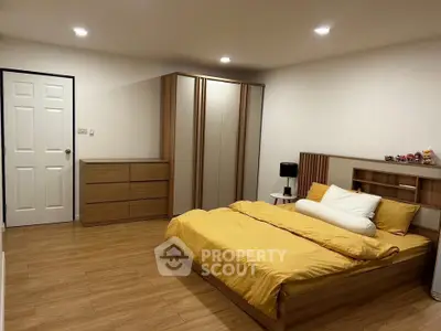 Spacious modern bedroom with wooden flooring and stylish furniture