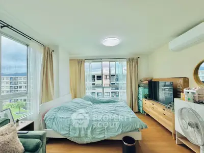 Spacious bedroom with large windows offering stunning city views, modern furnishings, and ample natural light.