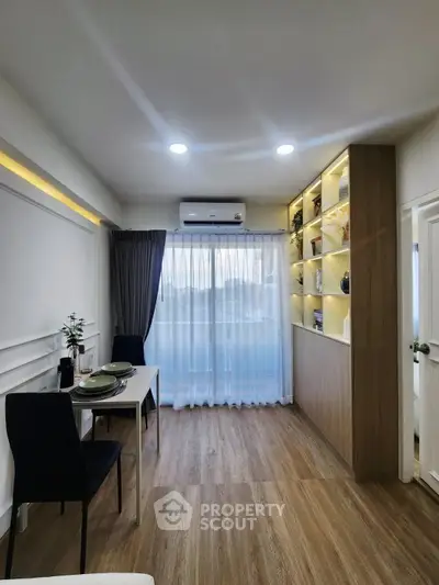 Modern living room with elegant decor and natural light, featuring a dining area and stylish shelving.