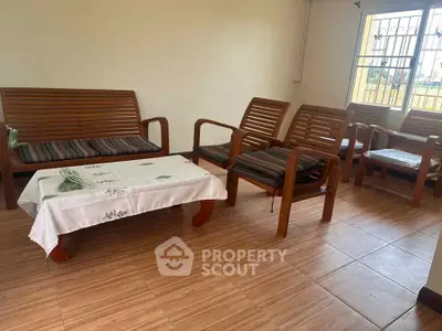 Cozy living room with wooden furniture and tiled flooring, perfect for relaxation.