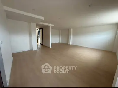 Spacious empty room with wooden flooring and modern design, ideal for customization.