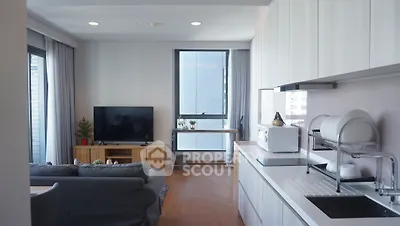 Modern open-layout living room with kitchen, featuring sleek cabinetry and cozy seating area.