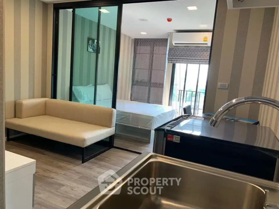 Modern studio apartment with open layout, featuring a cozy living area and a sleek kitchen.