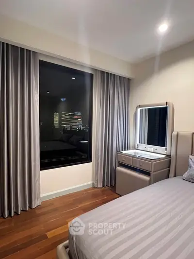 Elegant bedroom with large window and modern furnishings in a high-rise apartment.