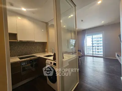 Modern apartment with sleek kitchen and spacious living area featuring large windows and balcony access.