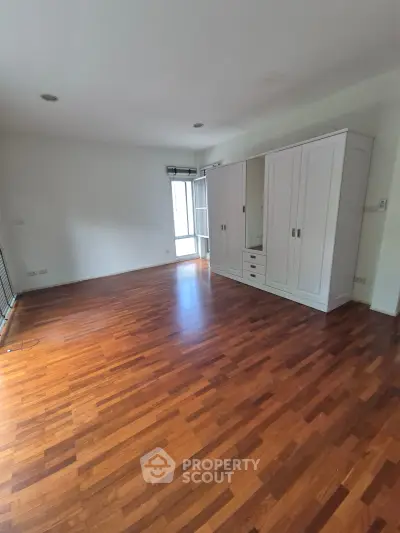 Spacious bedroom with wooden flooring and large wardrobe, perfect for modern living.