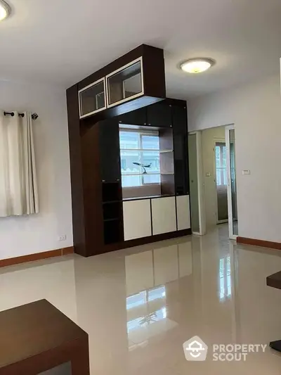 Spacious modern living room with sleek built-in shelving and glossy tiled floors.