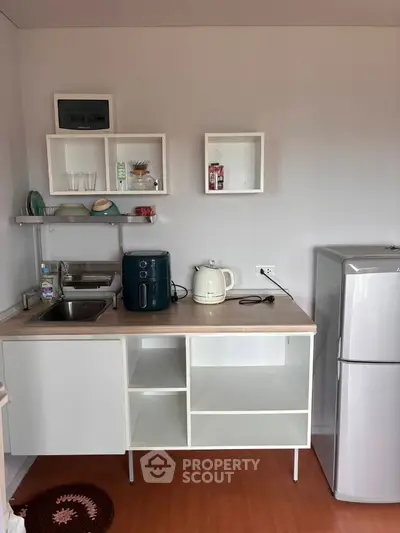 Compact kitchen with modern appliances and open shelving in a cozy apartment.