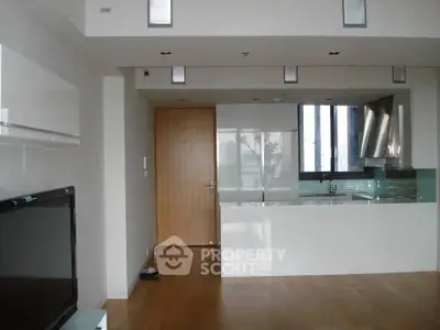 Modern open-layout kitchen with sleek cabinetry and hardwood floors in a stylish apartment.
