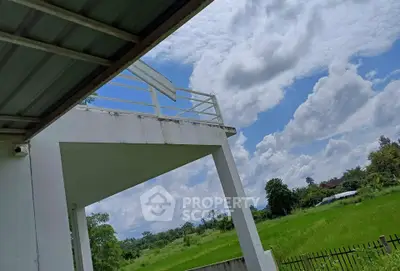 Stunning view from a modern building balcony overlooking lush green fields and blue skies.