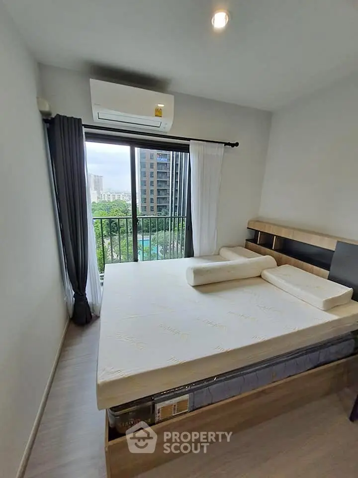 Modern bedroom with large window and city view, featuring a comfortable bed and air conditioning.