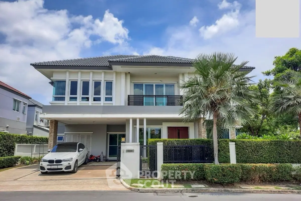 Stunning modern two-story house with lush greenery and luxury car in driveway.