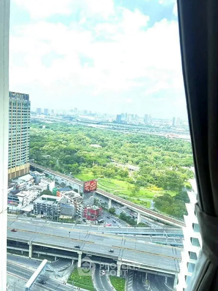 Stunning high-rise view of cityscape and lush greenery from a modern apartment window.