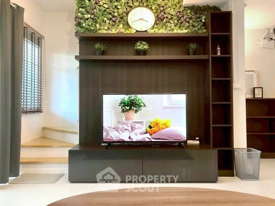 Modern living room with stylish TV unit and lush green wall decor