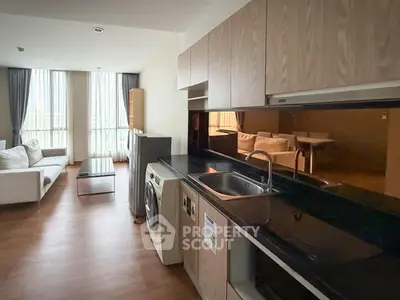 Modern open-layout apartment with sleek kitchen and spacious living area, featuring large windows and stylish furnishings.