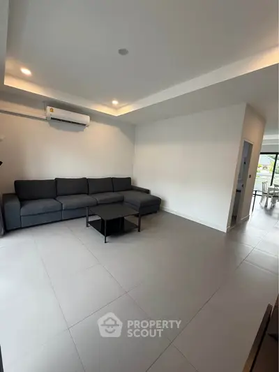 Spacious modern living room with sleek gray sofa and minimalist decor, perfect for relaxation and entertaining.