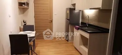 Modern kitchen with dining area, featuring sleek cabinetry and wooden flooring.