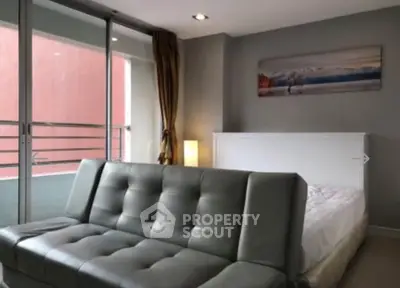Modern bedroom with sleek sofa and balcony access in urban apartment