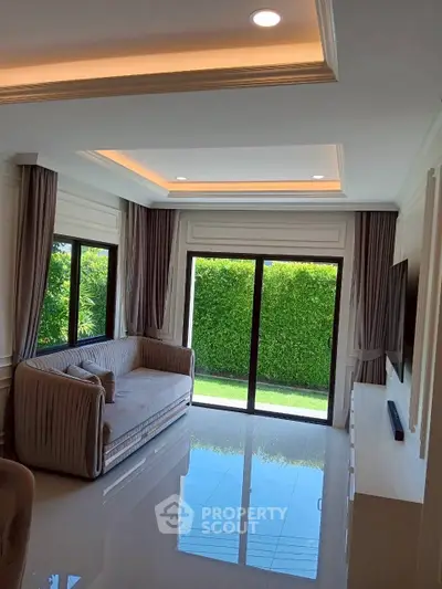 Elegant living room with large windows and garden view, featuring modern decor and ample natural light.