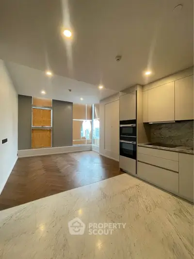 Modern open-layout kitchen with sleek cabinetry and spacious living area featuring large windows.