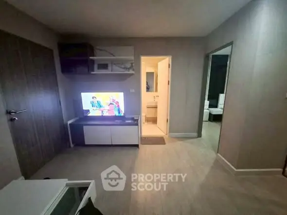 Cozy living room with modern decor and TV, leading to a bright bathroom and bedroom.