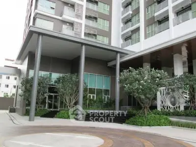 Modern apartment building entrance with landscaped greenery and sleek design.